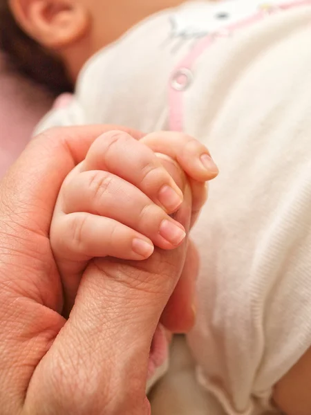 Parent holding an infants hand, small hand towards big — Stock Photo, Image
