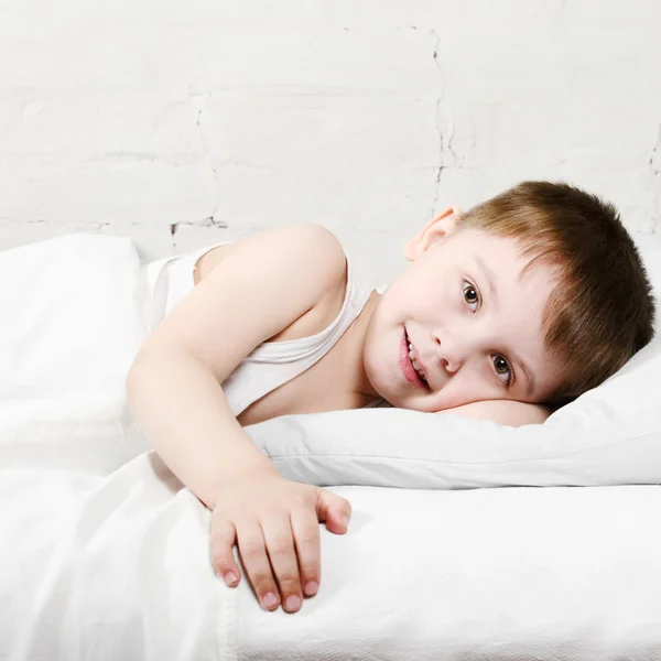 Chlapec s úsměvem v posteli — Stock fotografie
