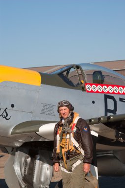 Pilot in WWII uniform near P-51 Mustang plane clipart