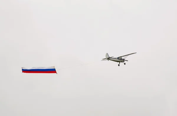 stock image Yak-12 tows Russian flag