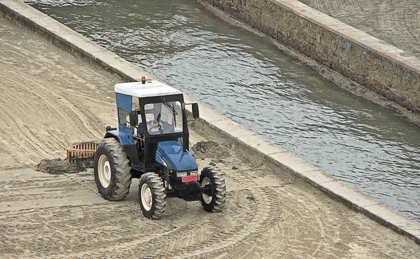 Tractor de nivelación azul esperando para limpiar la arena de la playa —  Fotos de Stock
