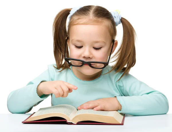 Linda niña lee un libro con gafas — Foto de Stock