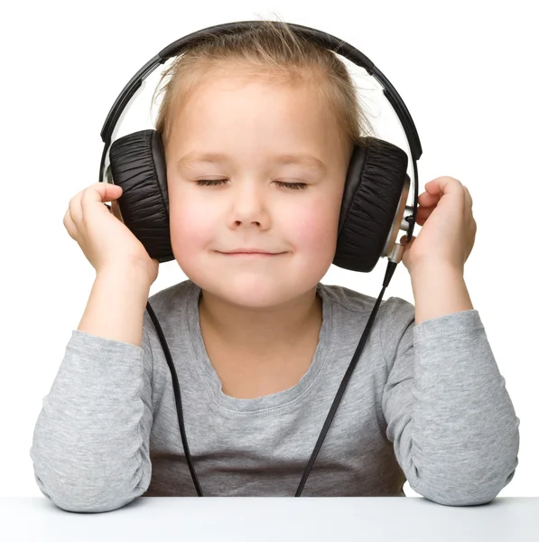 Linda niña disfrutando de la música usando auriculares — Foto de Stock