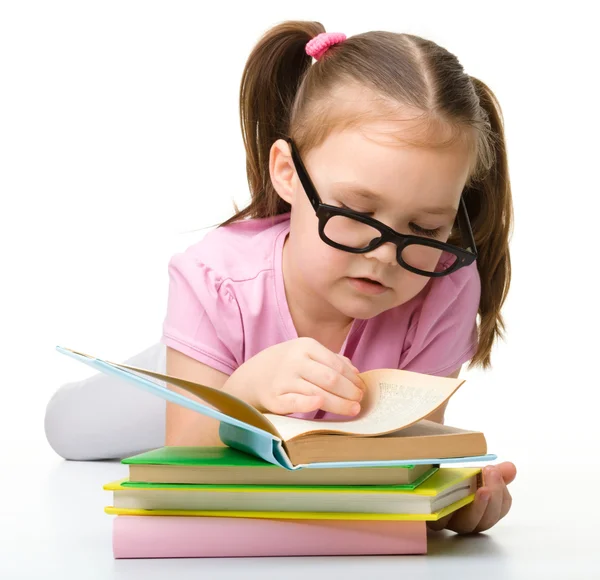 Милая маленькая девочка читает книгу в очках — стоковое фото