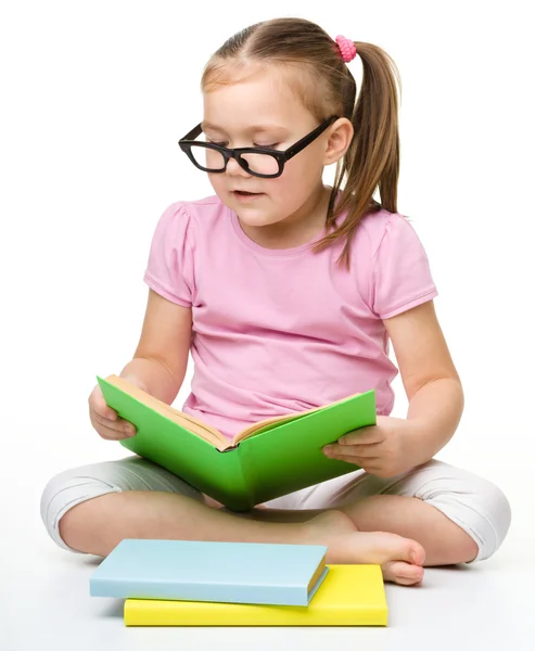Schattig klein meisje leest een boek dragen van een bril — Stockfoto