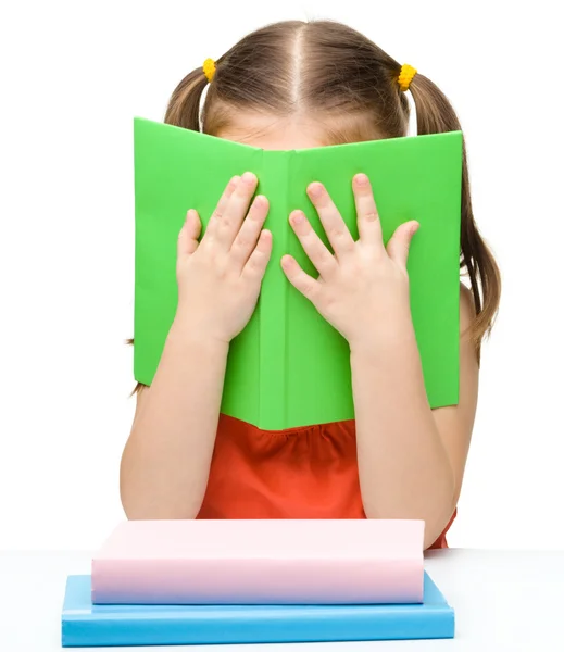 Roztomilá holčička se skrývá za knihu — Stock fotografie