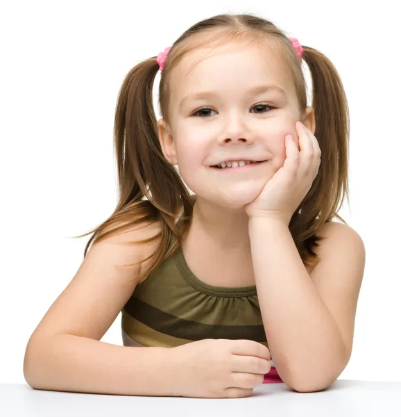 Szczęśliwa dziewczynka siedzi przy stole i uśmiech — Zdjęcie stockowe