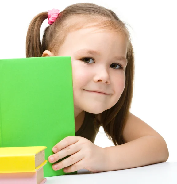 Cute little girl is hiding behind a book — Stock Photo, Image