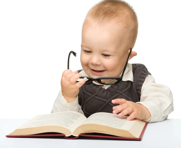 Criança brinca com livro e óculos — Fotografia de Stock