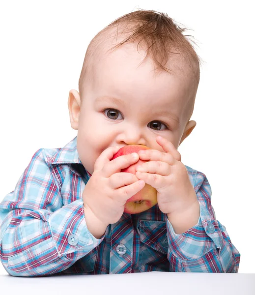 Criança está mordendo maçã vermelha e sorriso — Fotografia de Stock