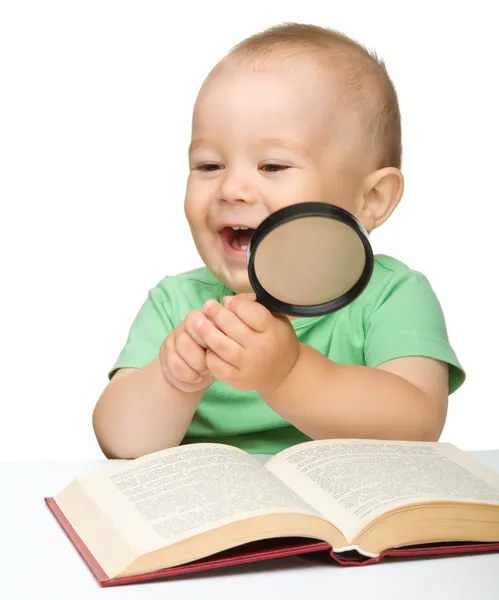 Liten barn lek med bok och förstoringsglas — Stockfoto