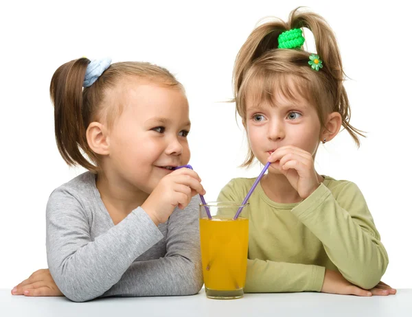 Two little girls are drinking orange juice — Stock Photo, Image