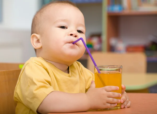 Pequeño niño está bebiendo jugo de naranja — Foto de Stock