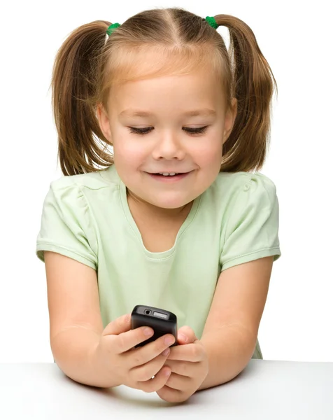 Schattig klein meisje speelt met mobiele telefoon — Stockfoto