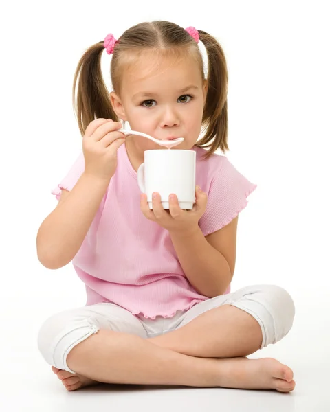 Cute little girl is eating yogurt — Stock Photo, Image