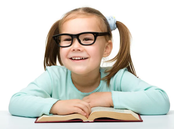 Menina lê um livro enquanto usa óculos — Fotografia de Stock
