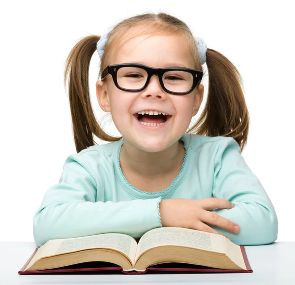 Little girl reads a book while wearing glasses — Stock Photo, Image