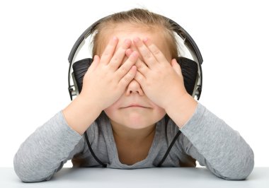 Unhappy girl listening music using headphones clipart