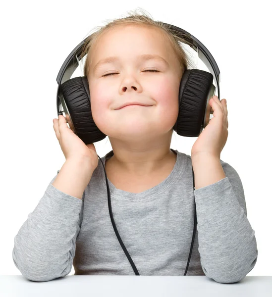 Linda chica disfrutando de la música usando auriculares — Foto de Stock