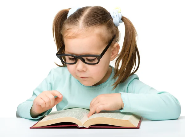La bambina legge un libro mentre indossa gli occhiali — Foto Stock