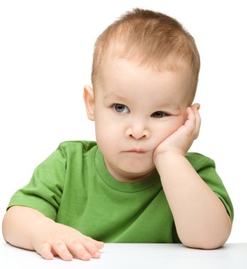 Pensive little boy support his head with hand clipart