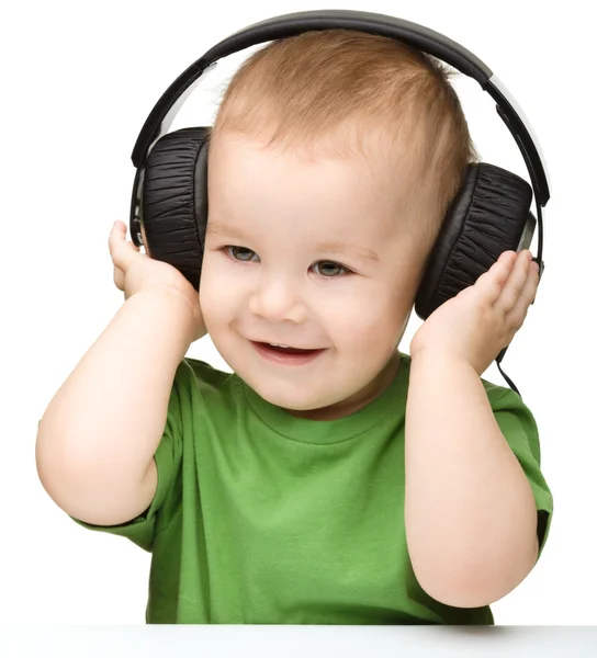 Lindo chico disfrutando de la música usando auriculares —  Fotos de Stock
