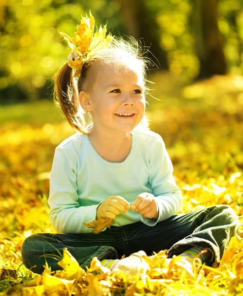 Χαριτωμένο μικρό κορίτσι παίζει με φύλλα στο πάρκο — Φωτογραφία Αρχείου