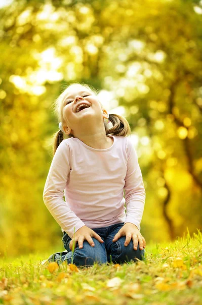 Schattig klein meisje speelt met bladeren in park — Stockfoto