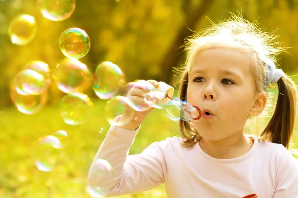 Маленькая девочка надувает мыльные пузыри — стоковое фото