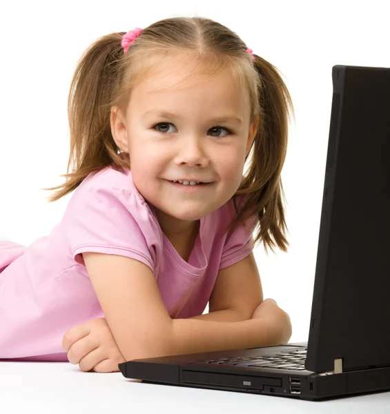Linda niña está sentada en el suelo con el ordenador portátil — Foto de Stock