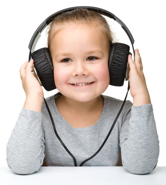Linda niña disfrutando de la música usando auriculares — Foto de Stock