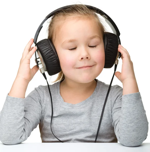 Linda niña disfrutando de la música usando auriculares —  Fotos de Stock