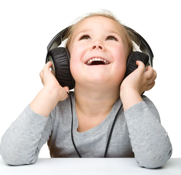 Linda niña disfrutando de la música usando auriculares — Foto de Stock