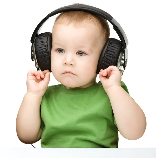 Schattige kleine jongen genieten van muziek met behulp van de hoofdtelefoon — Stockfoto