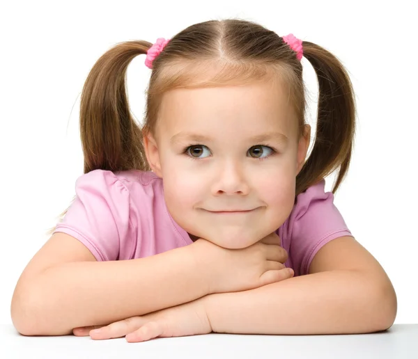 Щаслива маленька дівчинка сидить за столом і посміхається — стокове фото