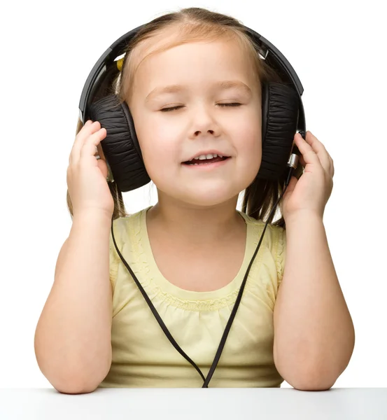 Милая маленькая девочка наслаждается музыкой в наушниках — стоковое фото