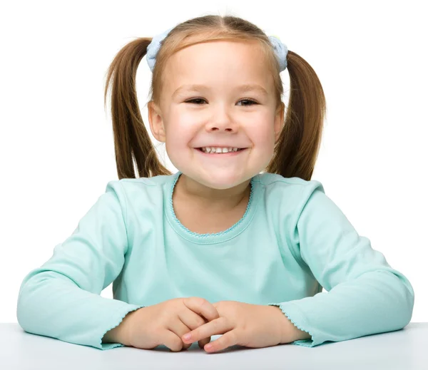 Счастливая маленькая девочка сидит за столом — стоковое фото