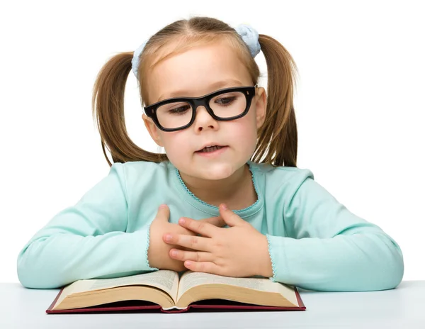 Linda niña lee un libro con gafas —  Fotos de Stock