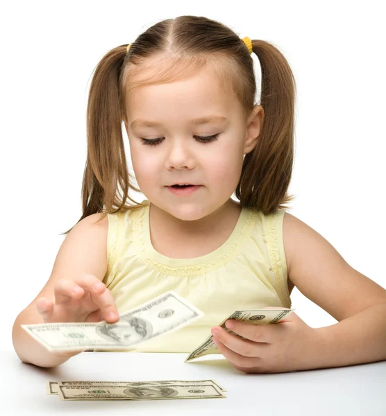 Nettes fröhliches kleines Mädchen zählt Dollars — Stockfoto