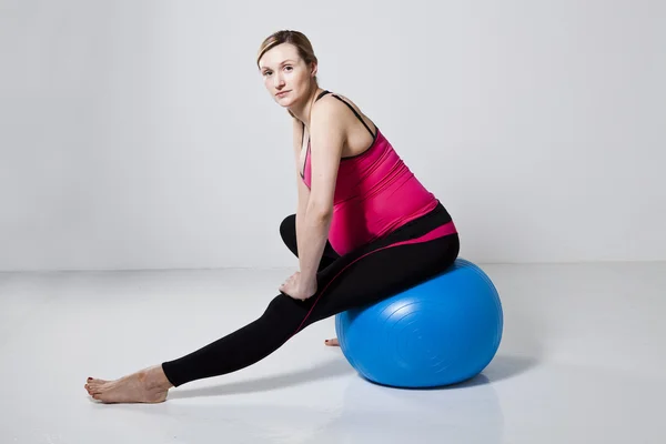 Pregnant woman stretching with fitness ball — Stock Photo, Image