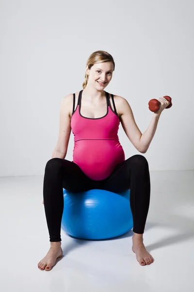 Беременная женщина тренируется с гантелями — стоковое фото