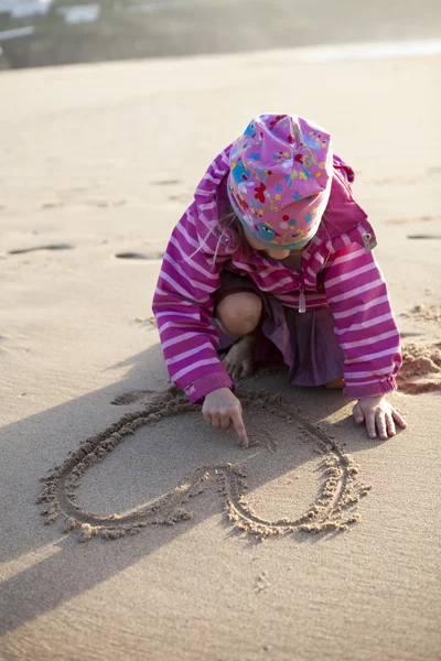 Mädchen zeichnet ein Herz in Sand — Stockfoto