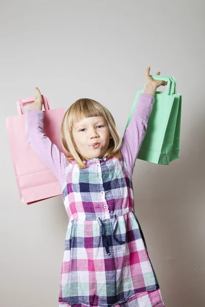 Little girl with shopping bags and lollipop — Stock Photo, Image