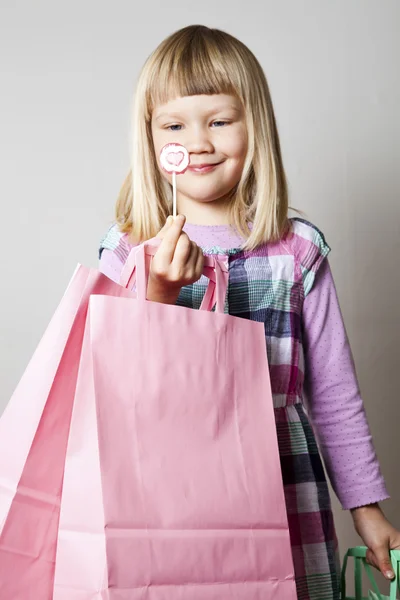 Little girl with shopping bags and lollipop — Stok fotoğraf