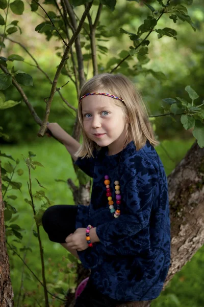 Menina sentada em um ramo de uma árvore de maçã — Fotografia de Stock