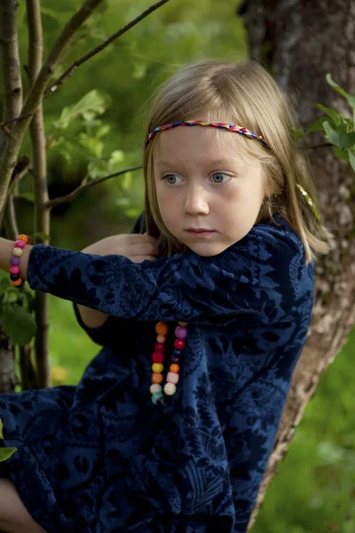 Kleines Mädchen sitzt auf einem Zweig eines Apfelbaums — Stockfoto