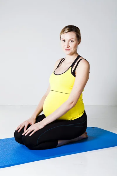 Беременная женщина стоит на коленях на коврике — стоковое фото