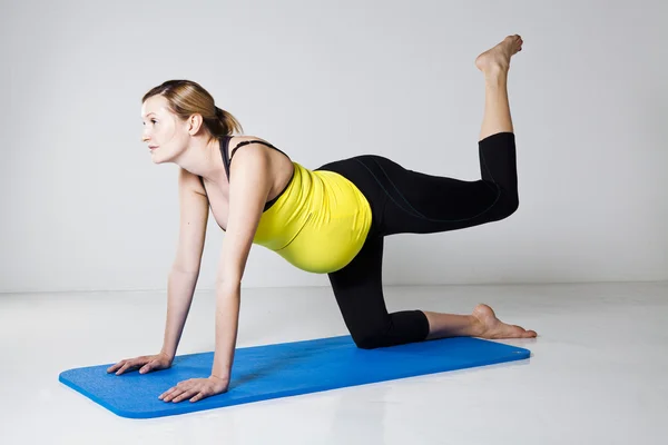 Pregnant woman exercising on mat — Stock Photo, Image