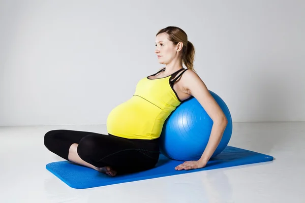 Mujer embarazada relajándose contra la pelota de fitness —  Fotos de Stock