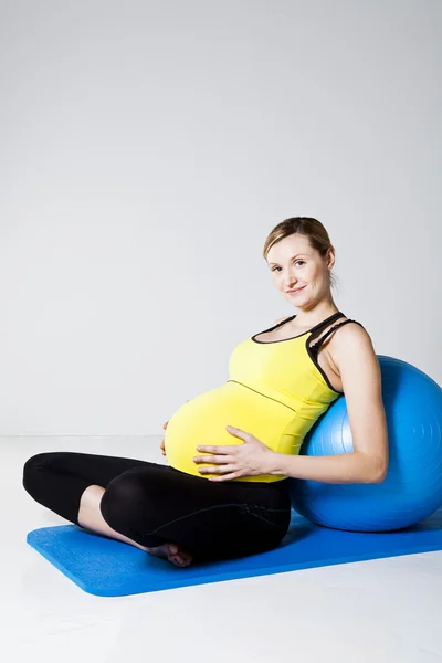 Беременная женщина расслабляется против фитнес-мяч — стоковое фото